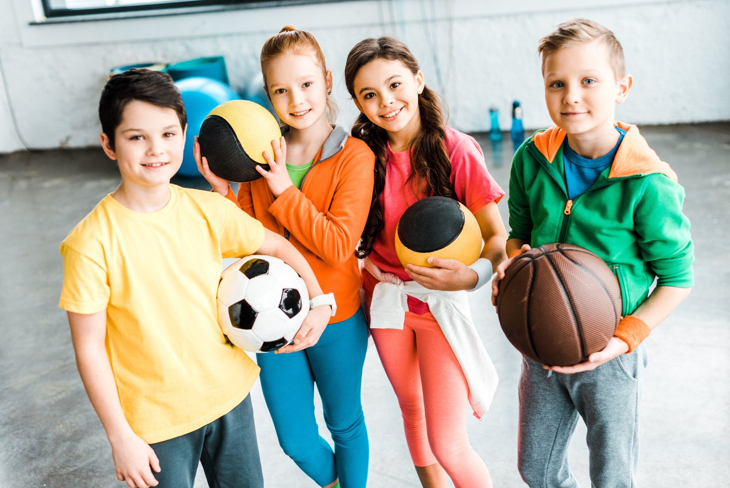 Excited children in sportswear posing with balls